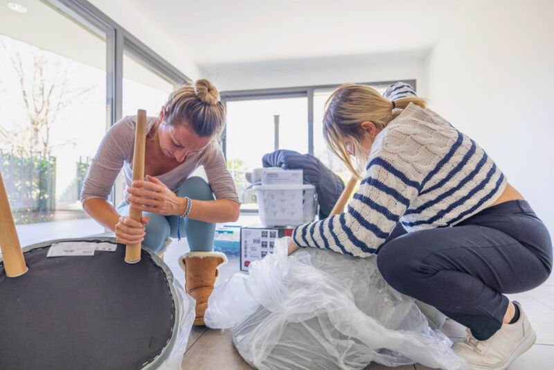 Zwei Frauen montieren gemeinsam Möbel in einer Wohnung.
