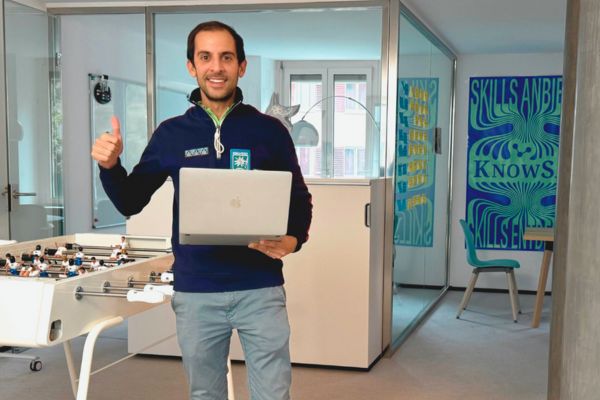 KnowS – Digital neighbourhood assistance in Switzerland A man holds up a laptop and smiles at the camera – a symbol of digital support and modern neighbourhood assistance with KnowS.