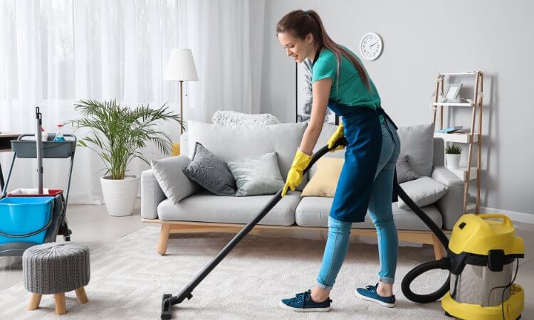 Reinigungskraft bei der Arbeit Eine Haushaltshilfe reinigt das Wohnzimmer und sorgt für Sauberkeit und Ordnung.