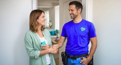 Woman greeting a handyman in her apartment after finding help through KnowS
